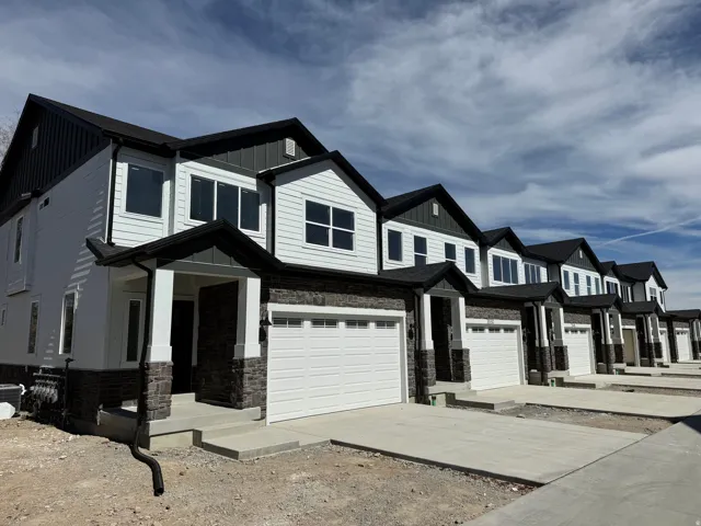 View of front facade featuring board and batten siding, stone siding, driveway, and an attached garage