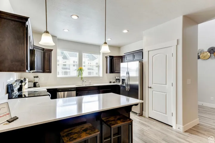 Kitchen with a peninsula, a breakfast bar, dark wood finish cabinets, and black appliances