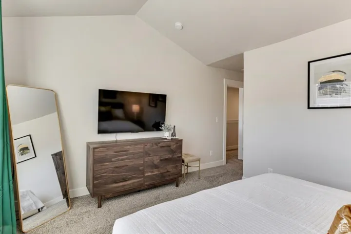 Bedroom featuring light carpet and lofted ceiling
