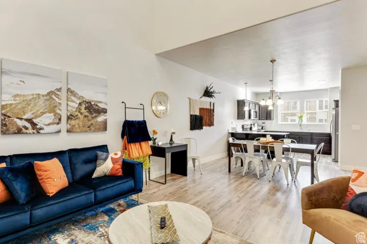 Living area with suspended lighting and light wood-type flooring