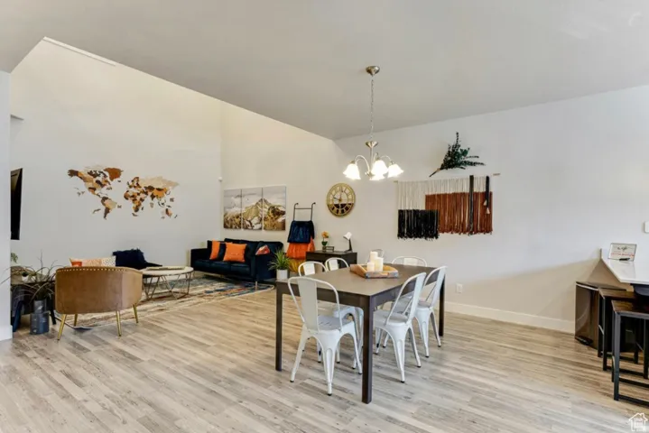 Dining area with light wood-style flooring, suspended lighting, and vaulted ceiling