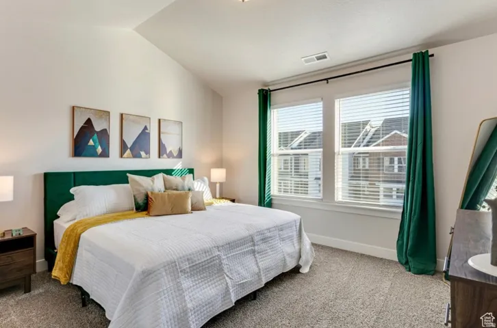 Carpeted bedroom featuring vaulted ceiling and baseboards