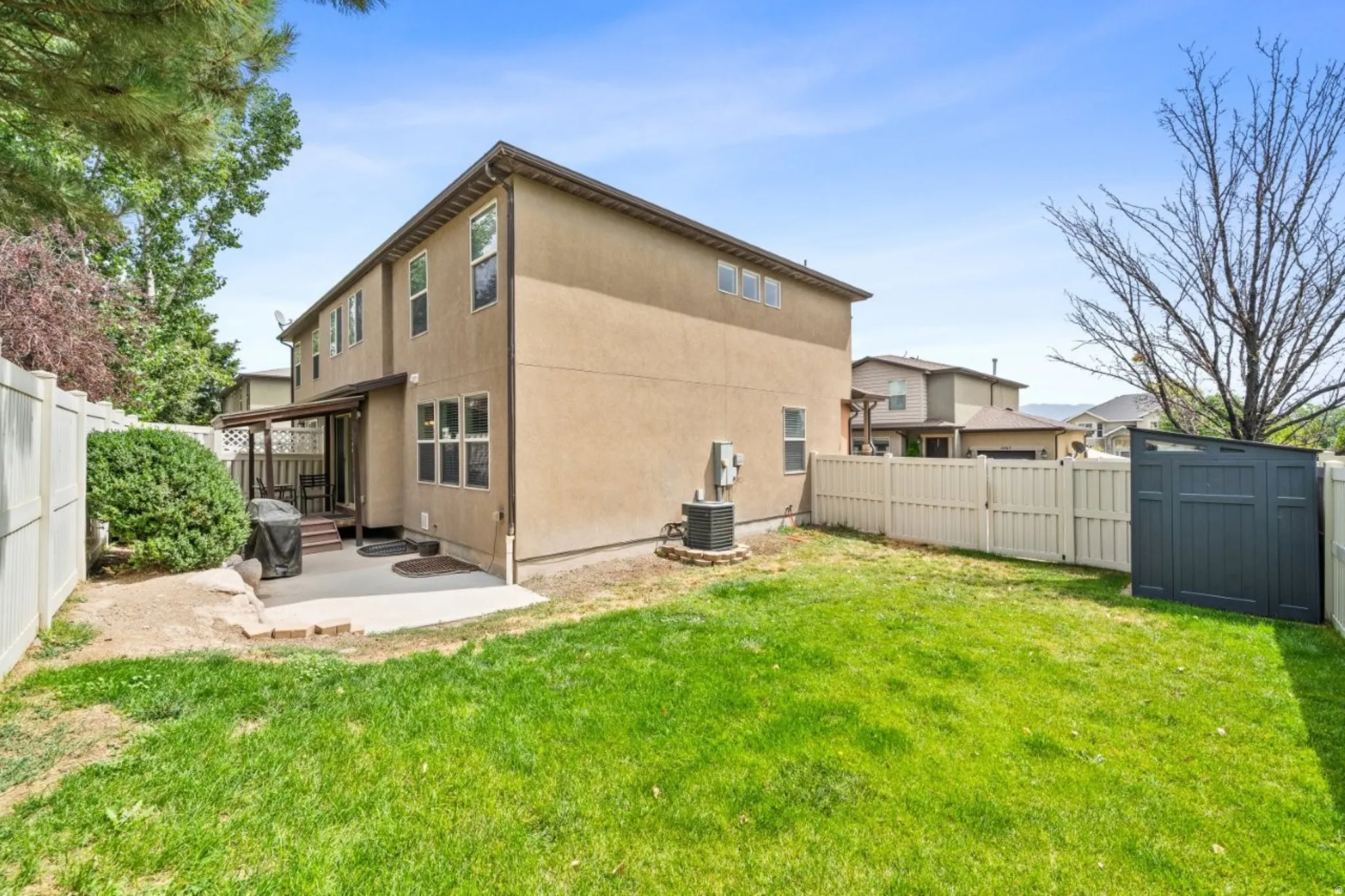 Rear view of property featuring a fenced backyard, a patio area, a shed, and stucco siding