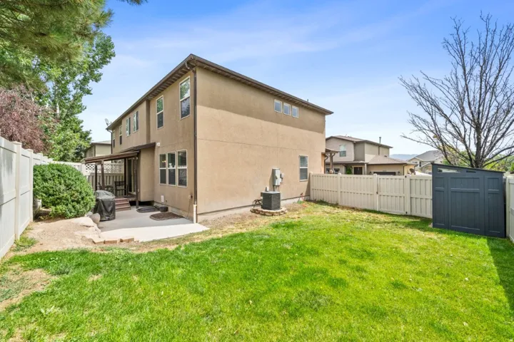 Rear view of property featuring a fenced backyard, a patio area, a shed, and stucco siding