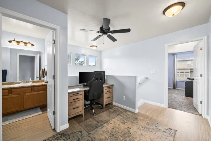 Office with dark wood-style floors and a ceiling fan
