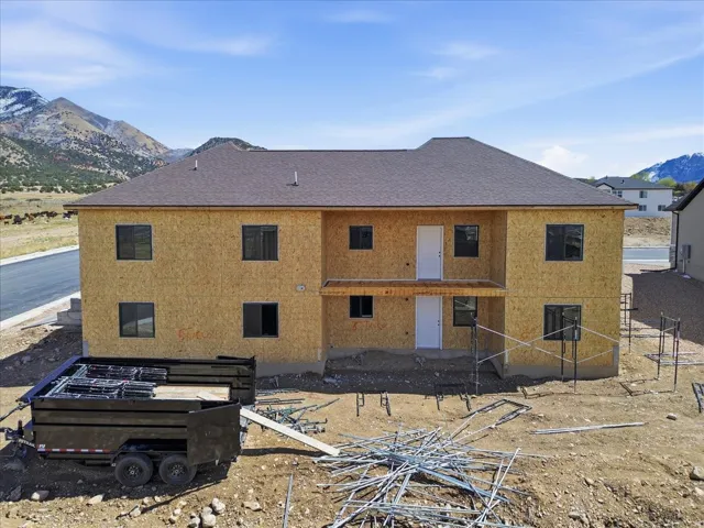 Back of property with a mountain view, a shingled roof, and a patio