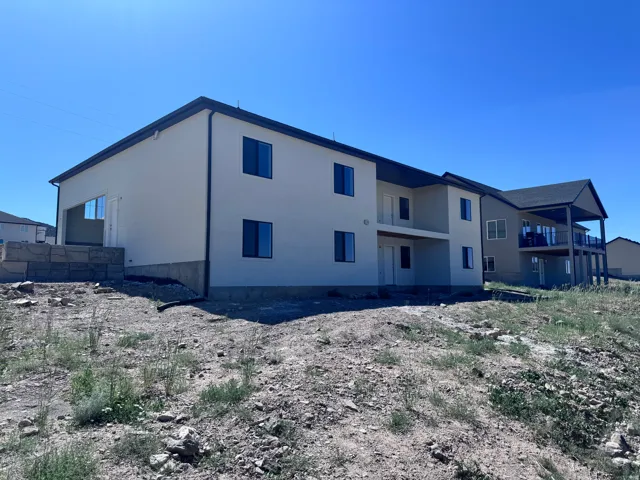 Modern multi-level residence featuring a stucco exterior, dark-framed windows, multiple balconies, and a covered patio area