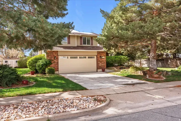 View of front of house featuring concrete driveway, a garage, brick siding, and a shingled roof