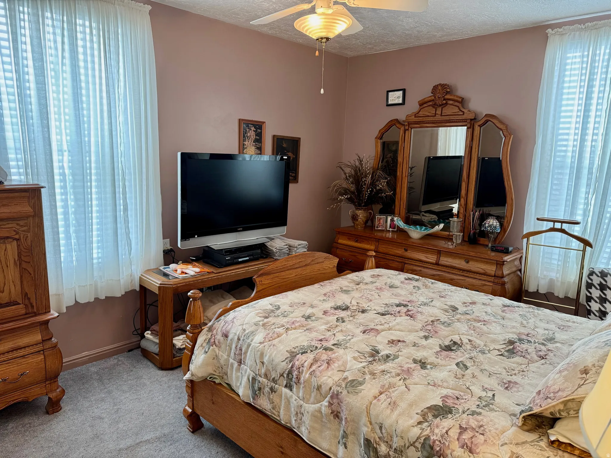 Bedroom with light colored carpet, ceiling fan, and a textured ceiling