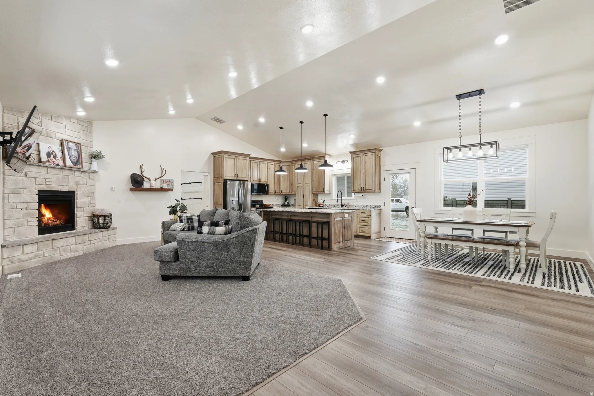 Living room with a stone fireplace, light wood-type flooring, and recessed lighting