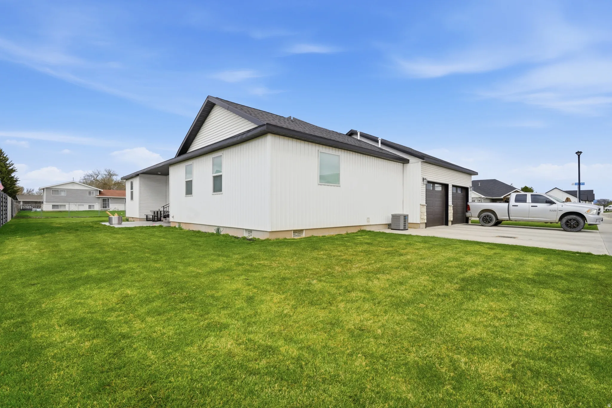 View of home's exterior with a lawn, concrete driveway, a garage, and a patio