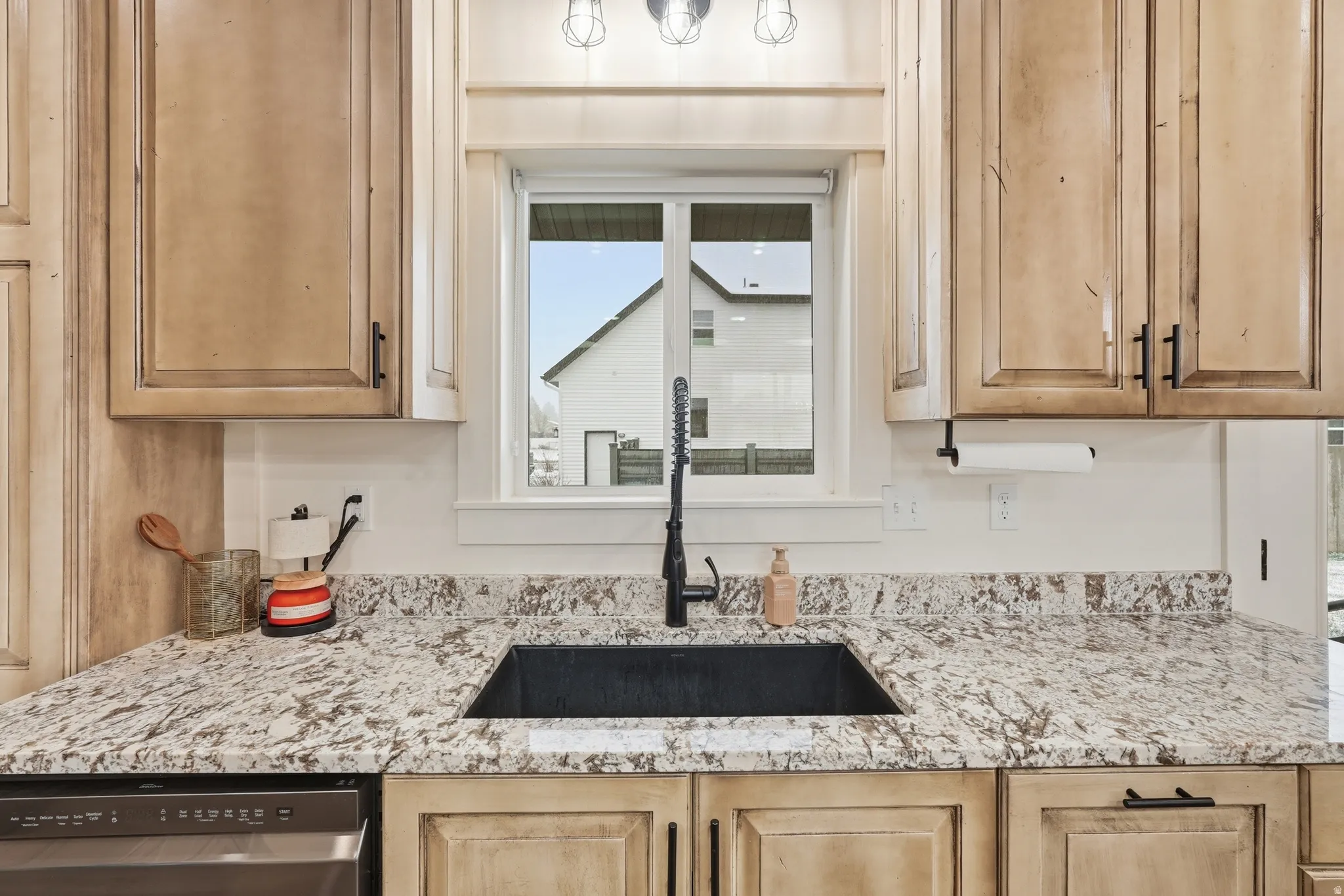 Kitchen featuring light stone countertops, dishwasher, and light wood finish cabinets