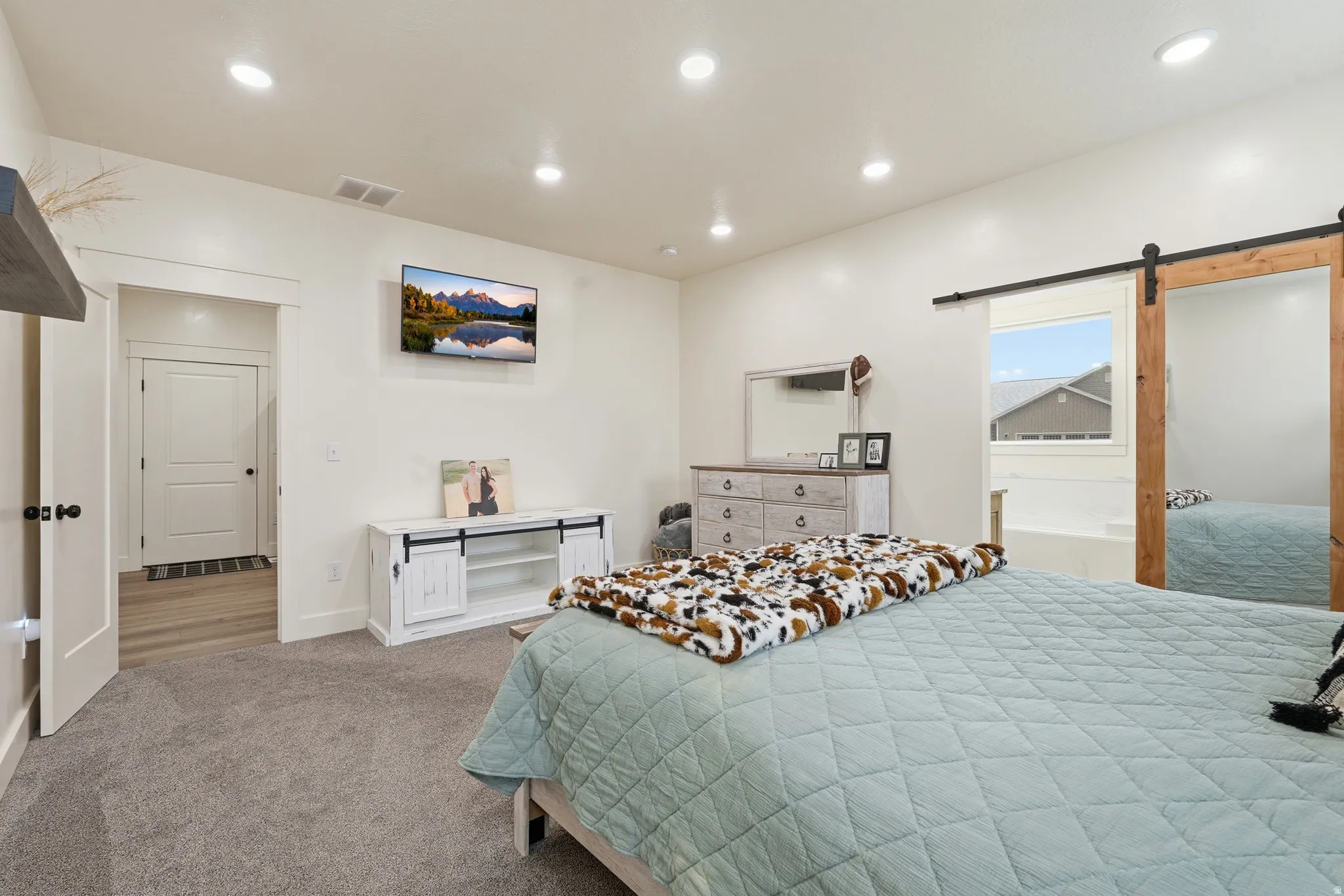 Bedroom with a barn door, carpet, and recessed lighting