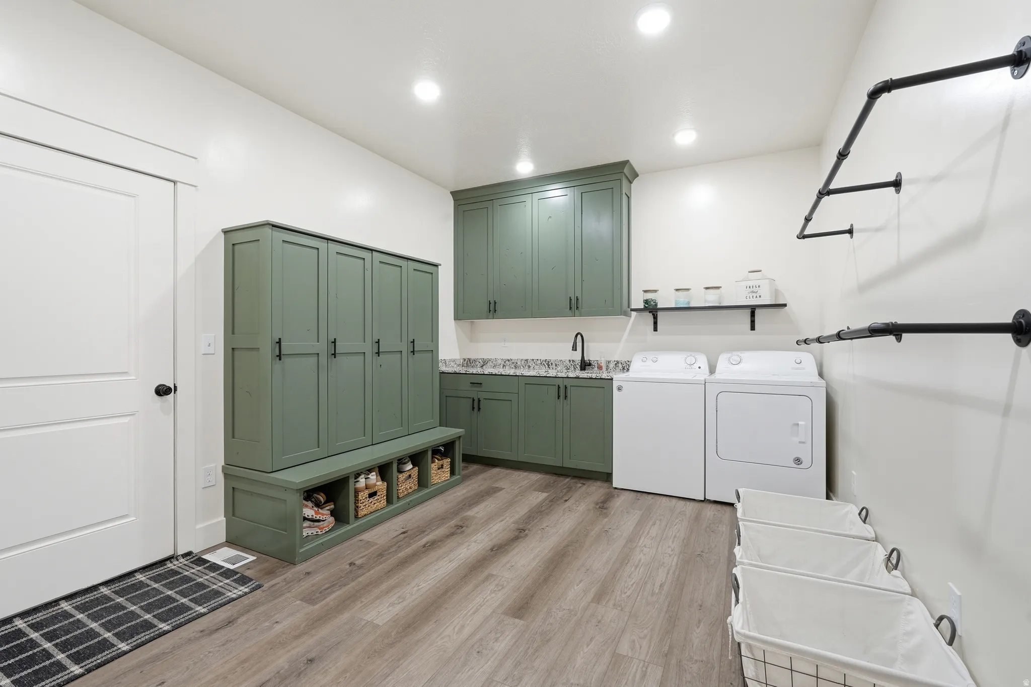 Laundry area with light wood finished floors, independent washer and dryer, recessed lighting, and cabinet space