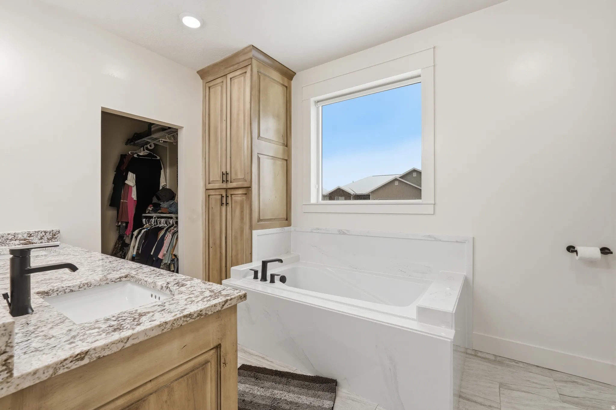 Bathroom featuring a walk in closet, a garden tub, double vanity, and recessed lighting