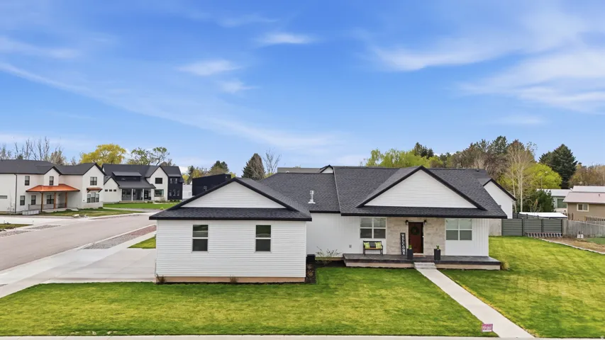 Modern farmhouse style home featuring a porch, roof with shingles, a residential view, and a front yard