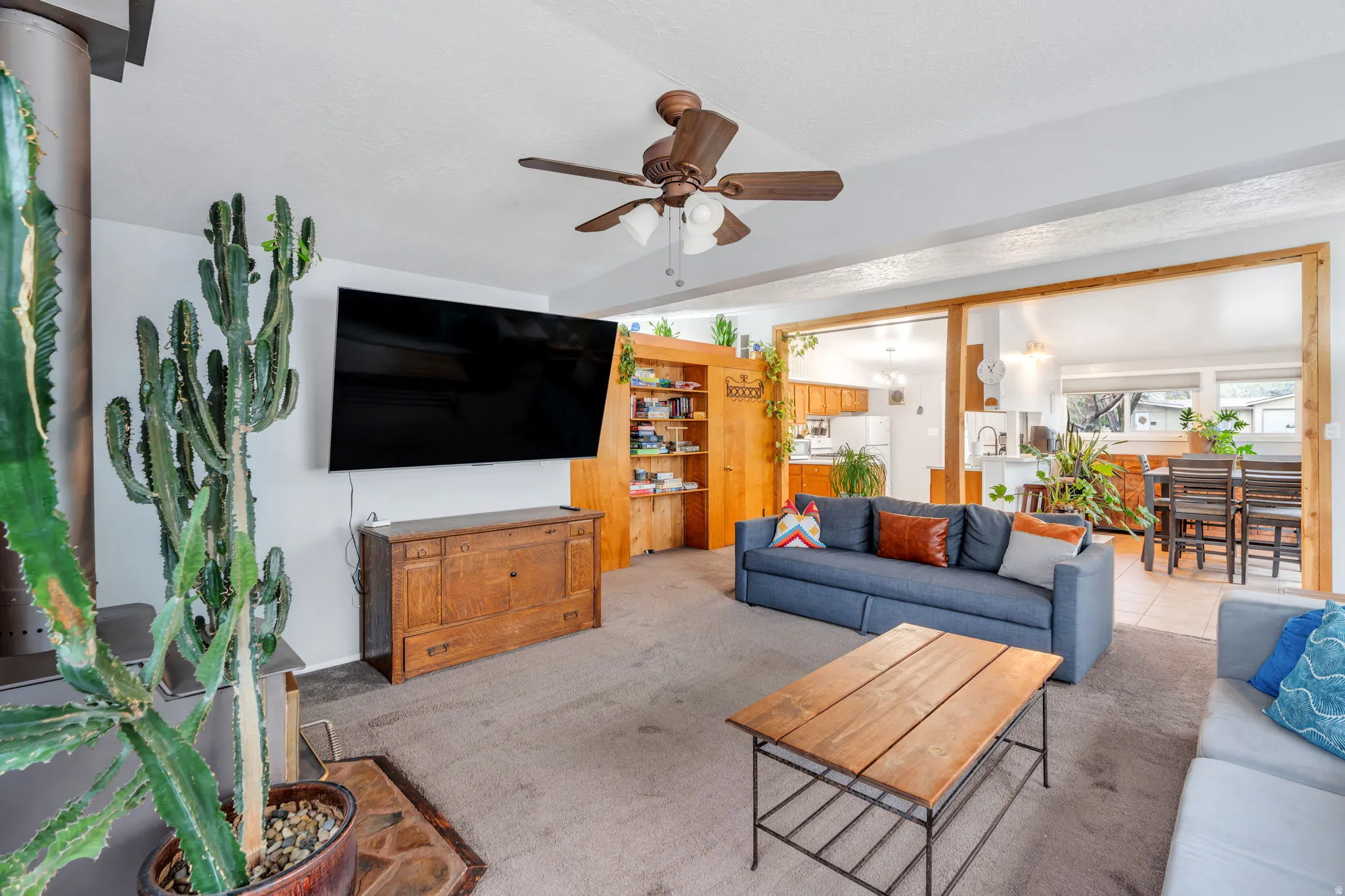 Living area with carpet flooring, ceiling fan, and lofted ceiling with beams