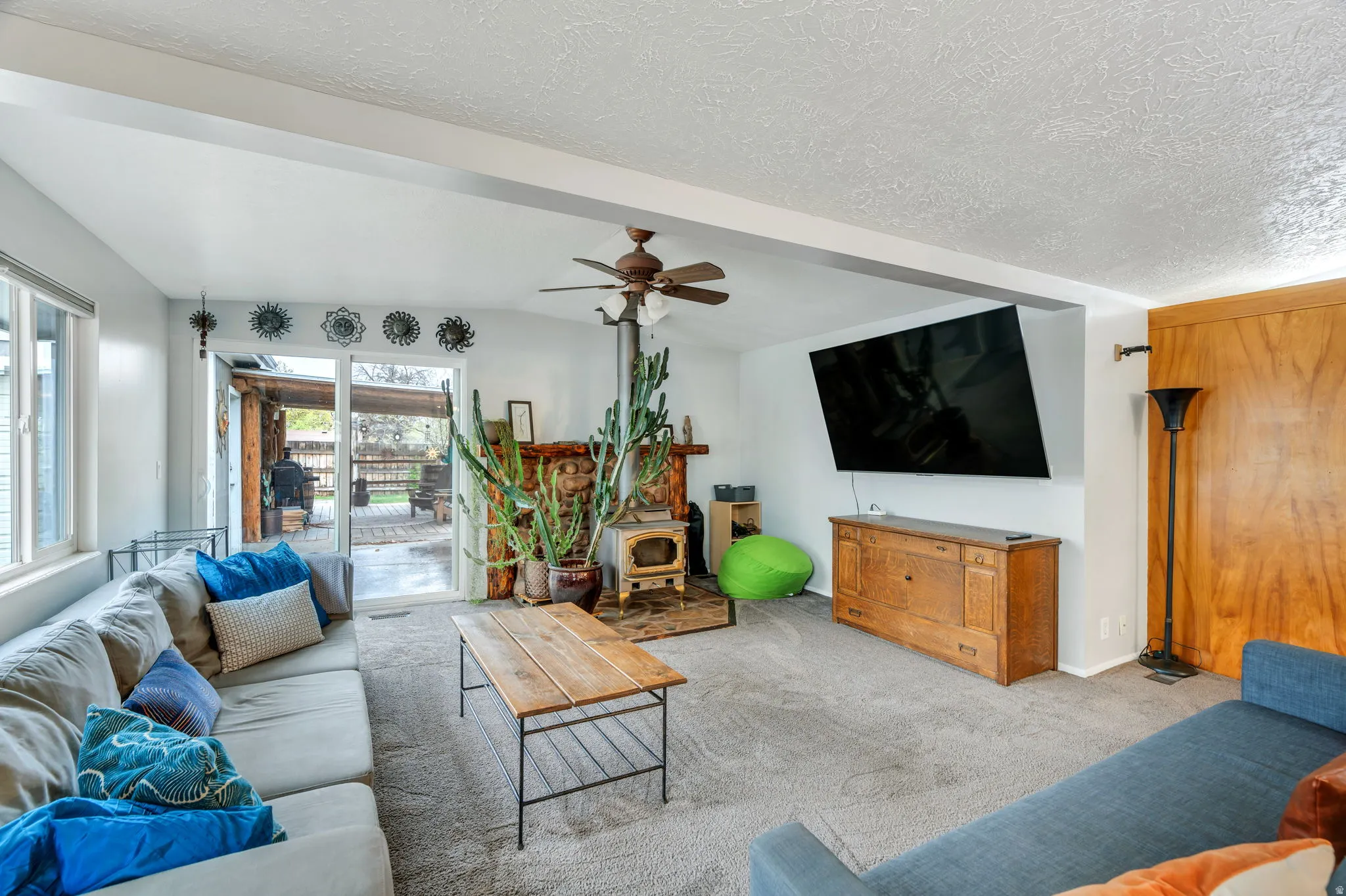 Carpeted living room featuring a ceiling fan and baseboards