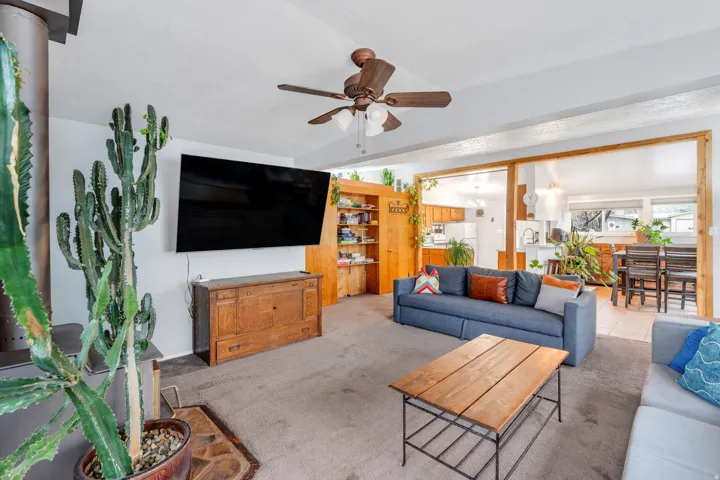 Living area with carpet flooring, ceiling fan, and lofted ceiling with beams