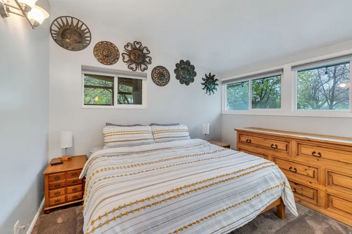 Bedroom with multiple windows, dark colored carpet, and lofted ceiling
