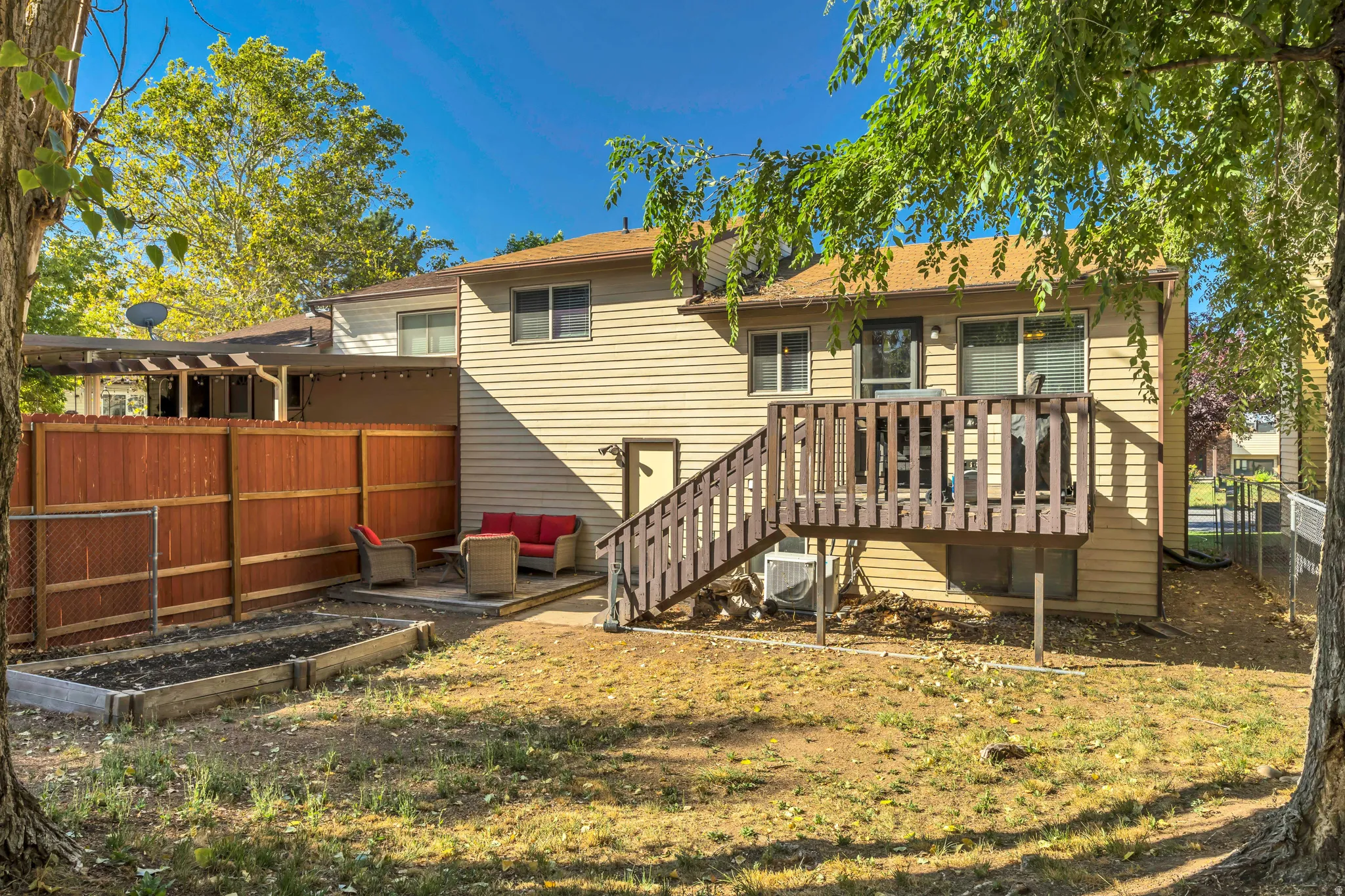 Back of property featuring a fenced backyard, a wooden deck, an outdoor living space, and a garden