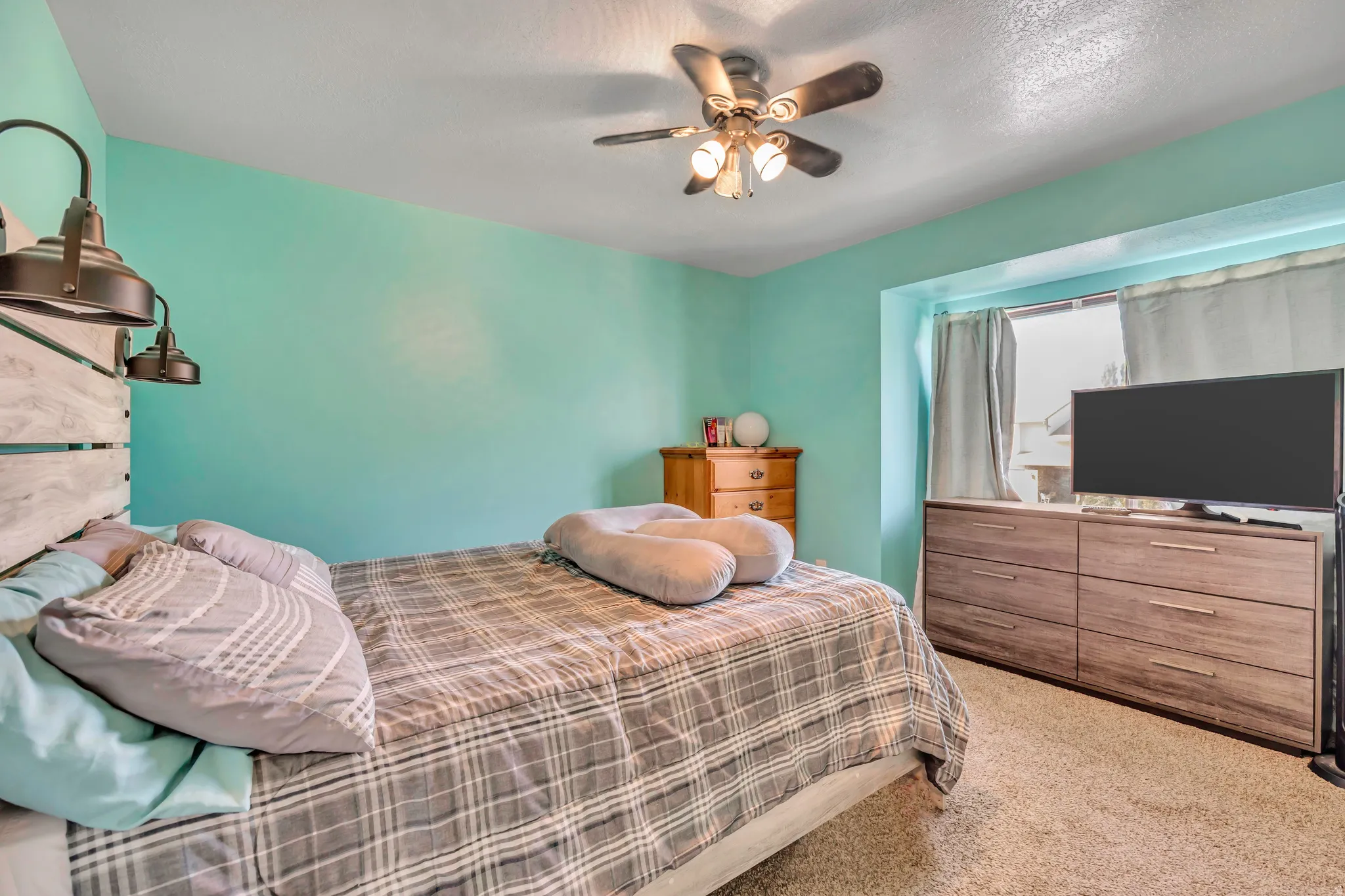 Bedroom featuring light carpet, ceiling fan, and a textured ceiling