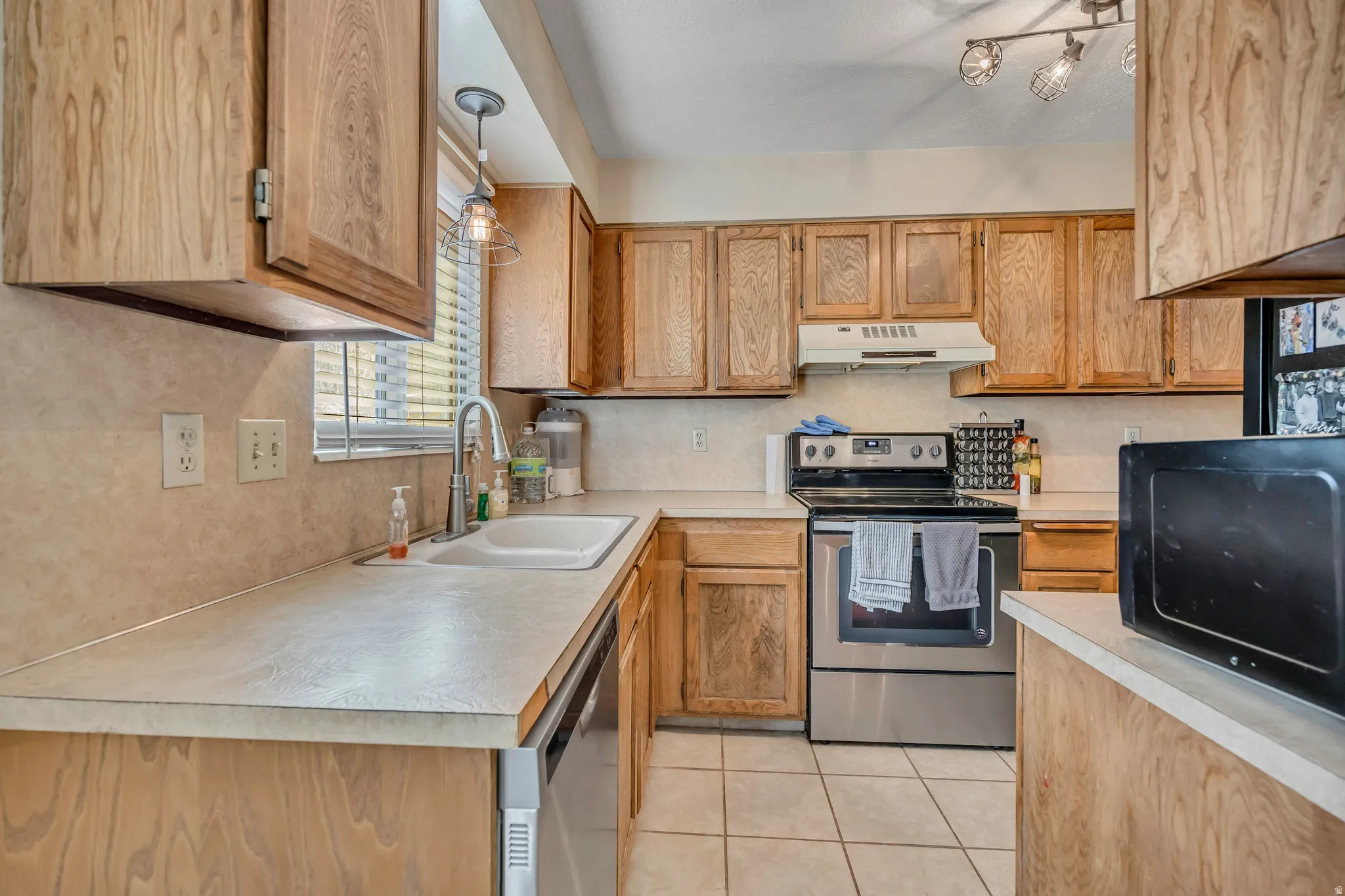 Kitchen featuring stainless steel appliances, light countertops, light tile patterned floors, and wood finish cabinets
