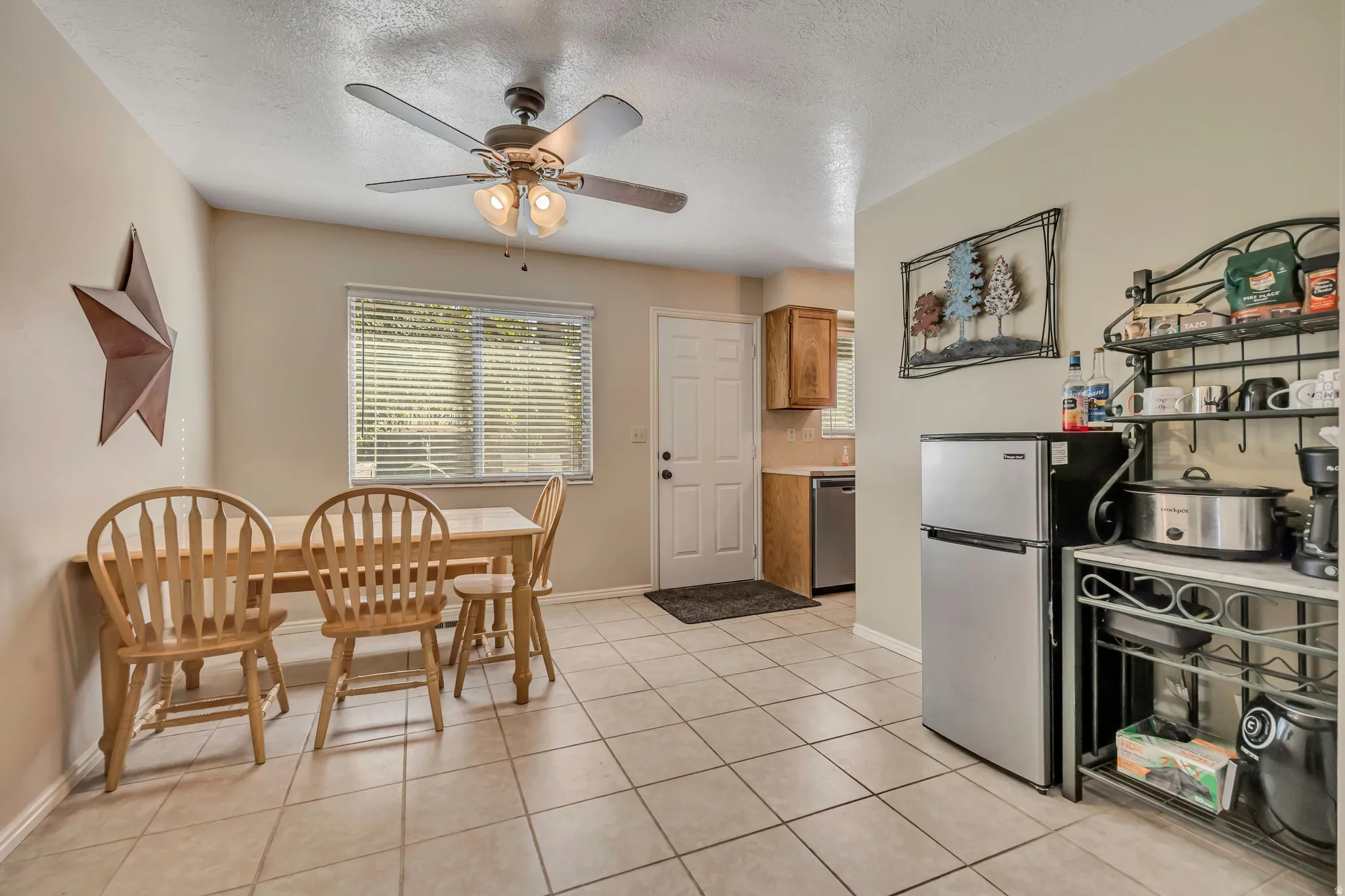 Kitchen with backsplash, stainless steel appliances, light tile patterned flooring, a textured ceiling, and wood finish cabinetry