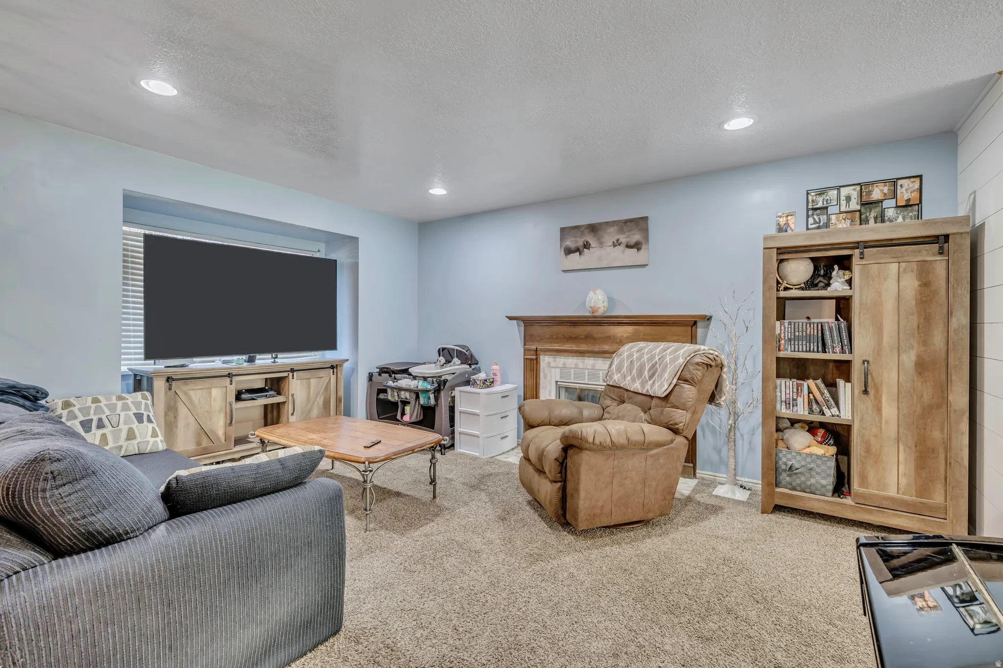 Living room with a tile fireplace, carpet flooring, recessed lighting, and a textured ceiling