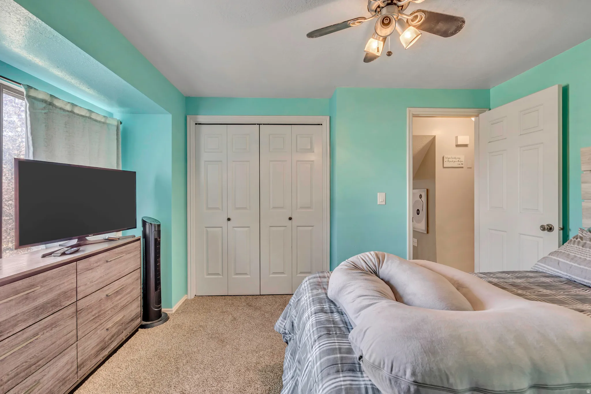 Bedroom with light carpet, a closet, and ceiling fan