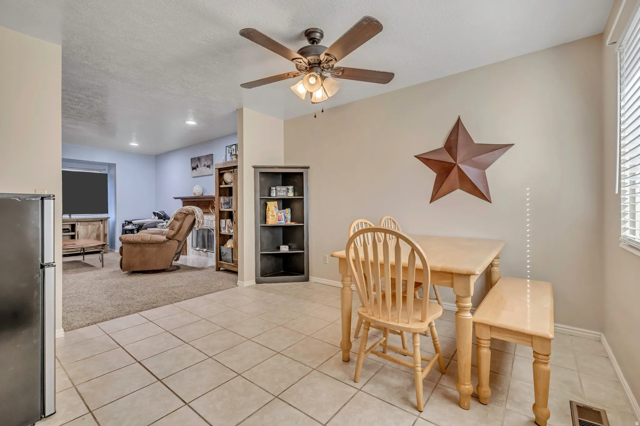 Dining space featuring a fireplace, ceiling fan, a textured ceiling, and light tile patterned flooring