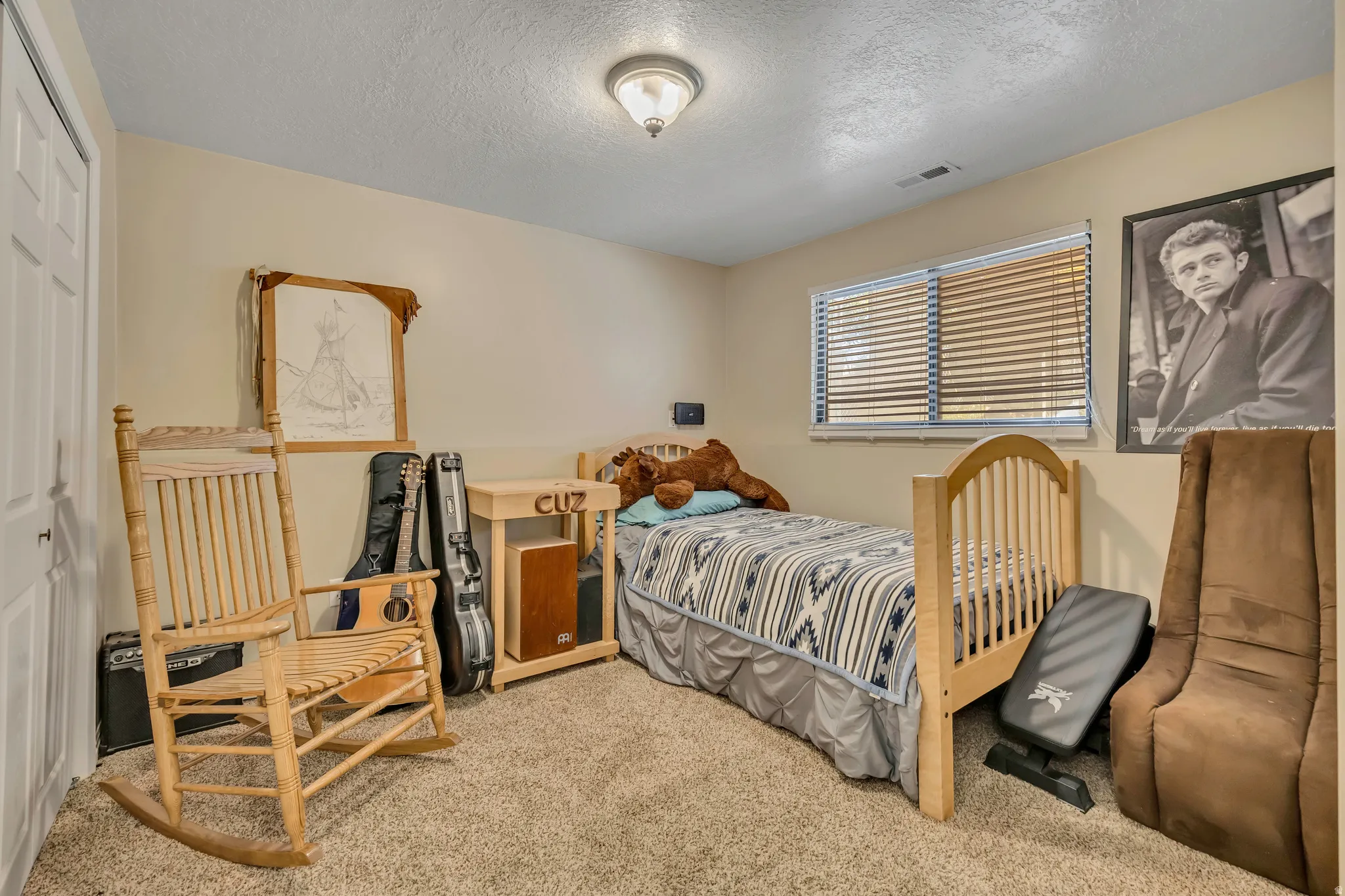 Bedroom with a textured ceiling, light carpet, and a closet