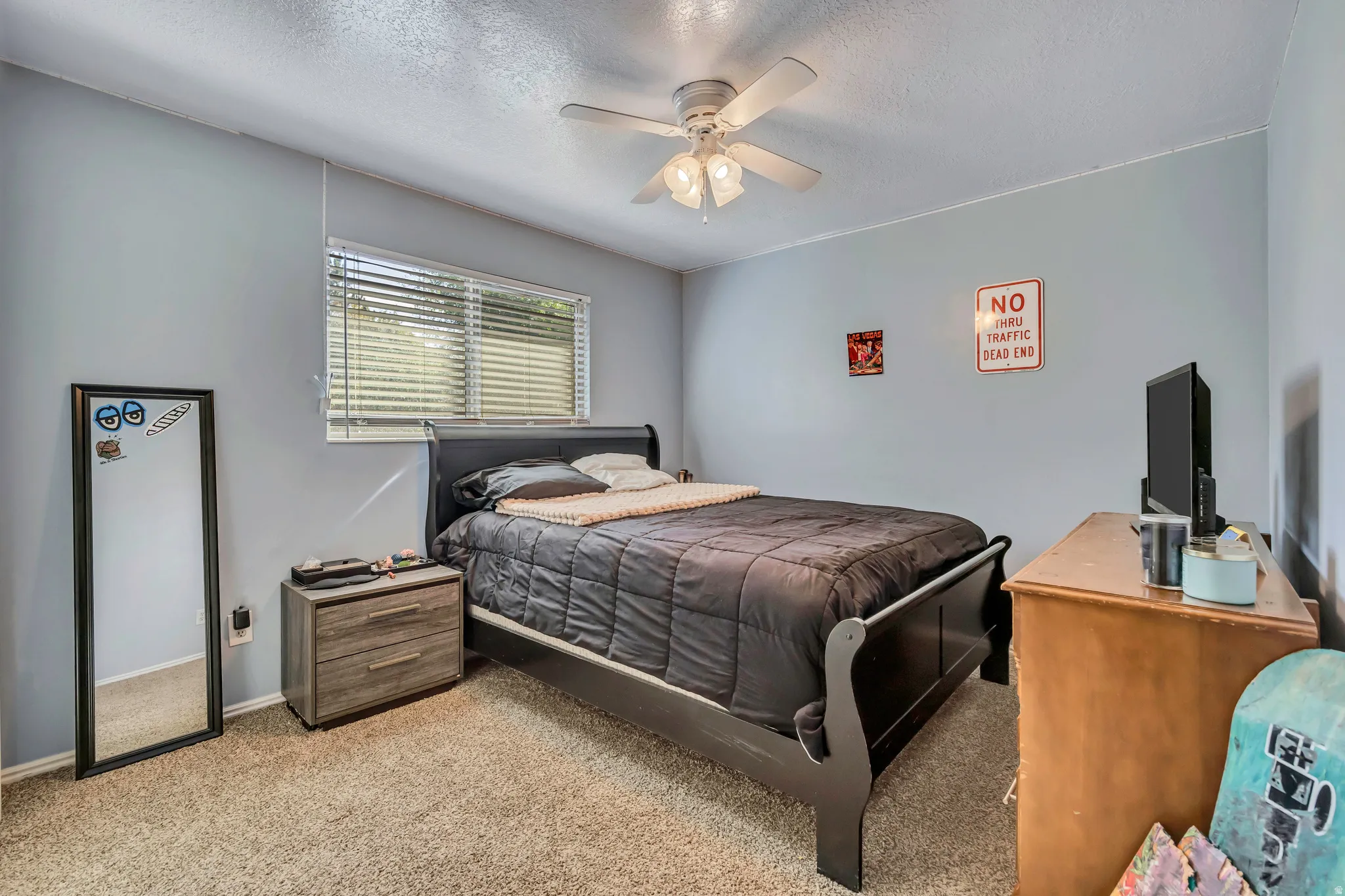 Carpeted bedroom featuring a ceiling fan and a textured ceiling