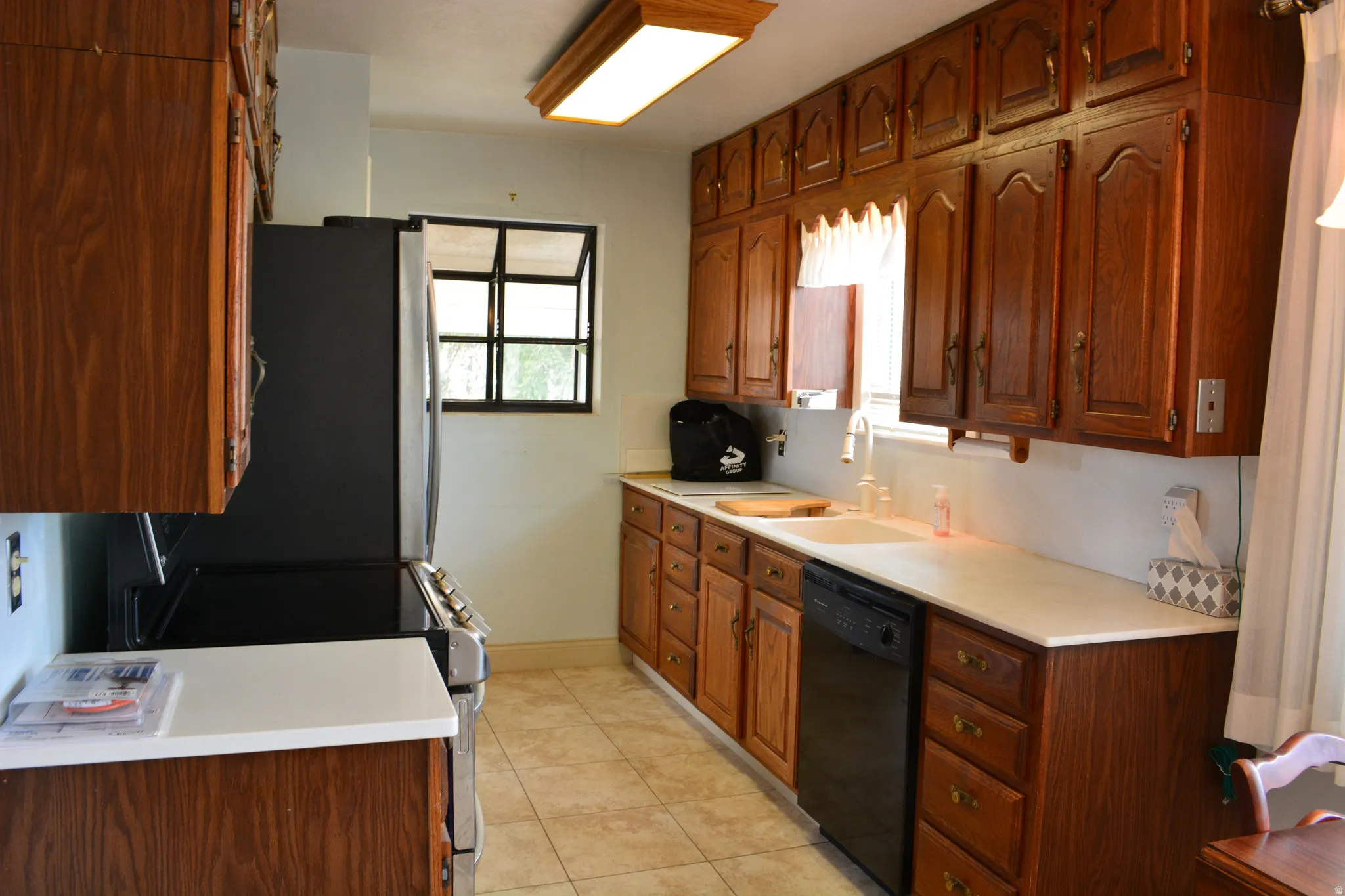 Kitchen with light countertops, stainless steel appliances, wood finish cabinets, and light tile patterned floors