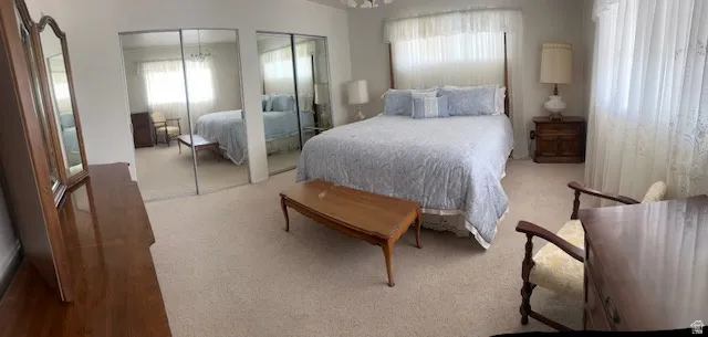 Carpeted bedroom featuring multiple closets and a chandelier