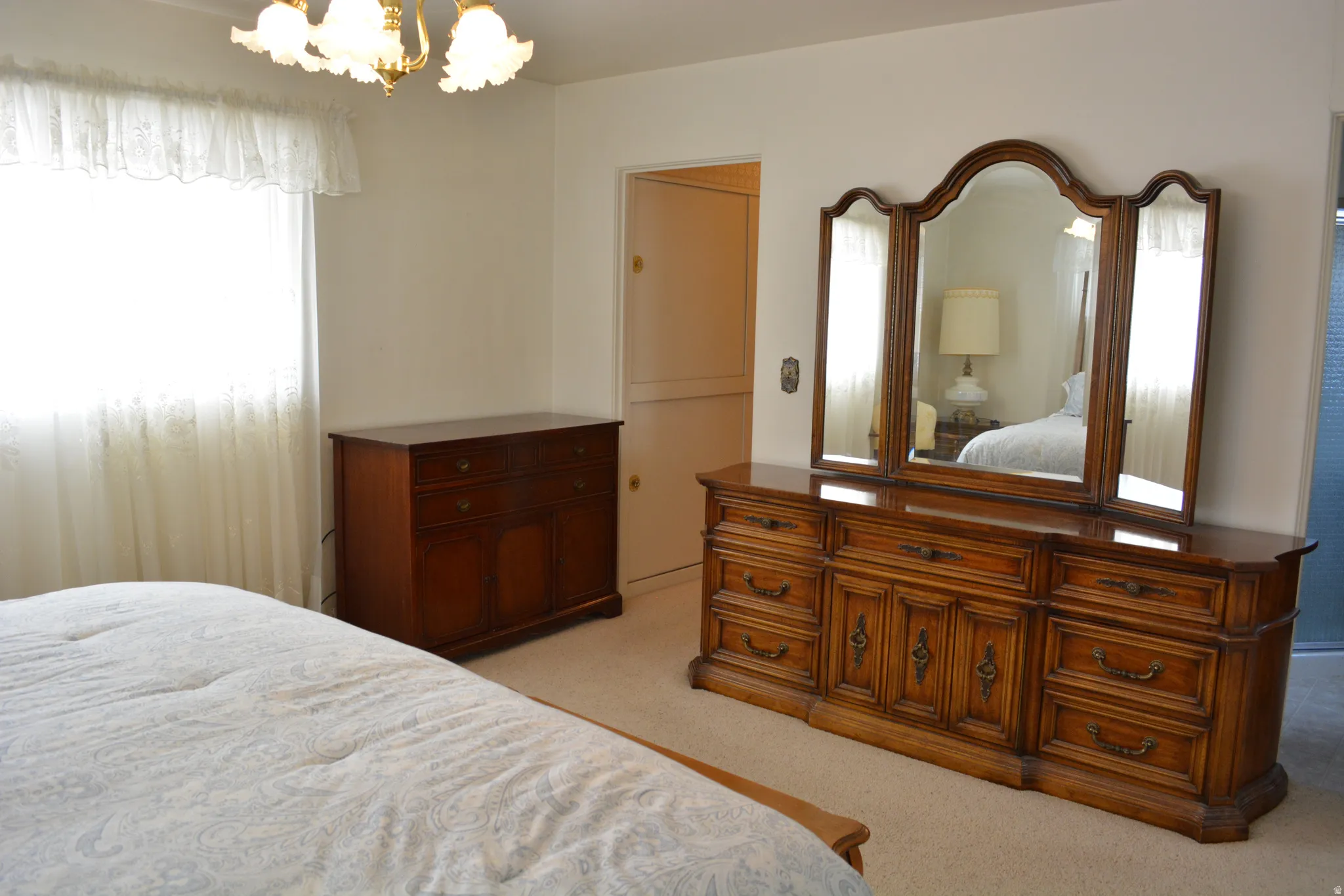 Bedroom with light colored carpet and suspended lighting