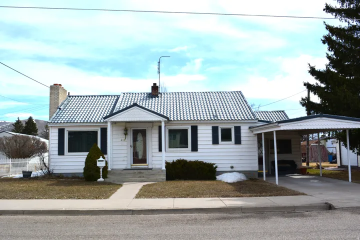 View of front of house featuring a chimney, concrete driveway, a tile roof, and an attached carport
