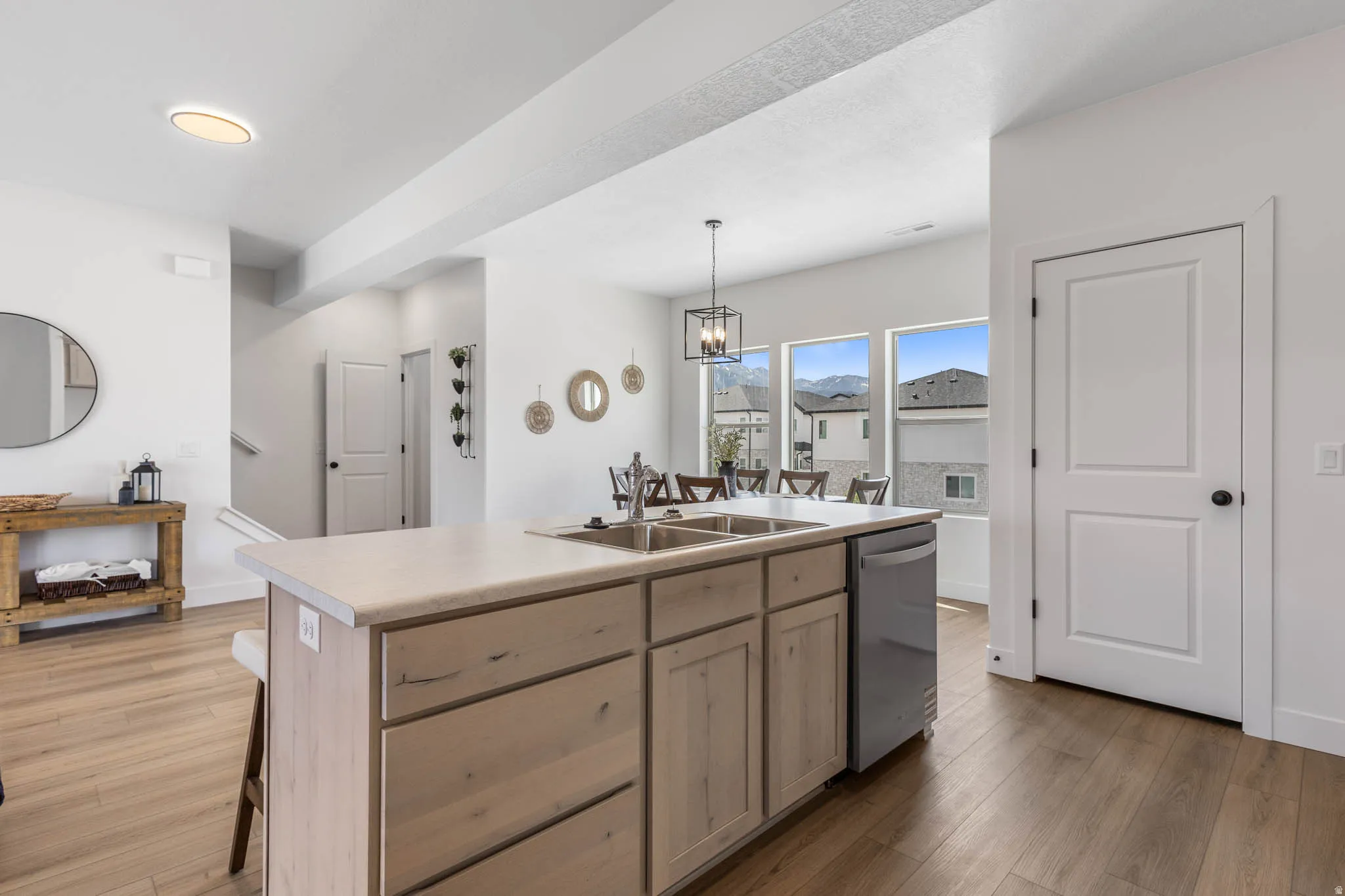 Kitchen with a center island with sink, light wood finish cabinetry, dark wood-style floors, and light countertops
