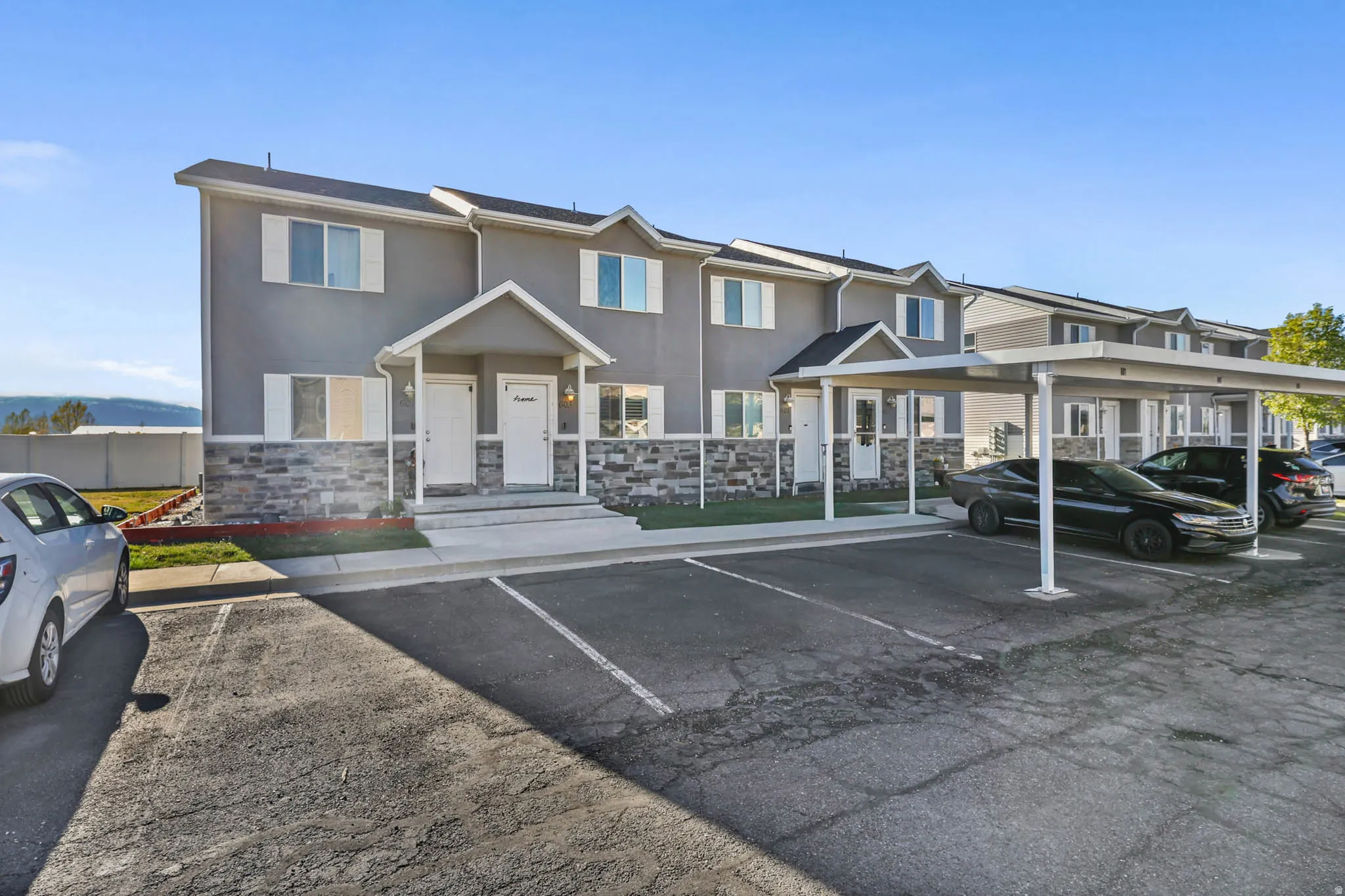 View of front of home featuring uncovered parking, stucco siding, and stone siding