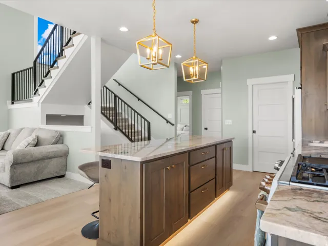 Spacious kitchen island with warm wood-finish cabinetry, under-cabinet lighting, and stone countertops