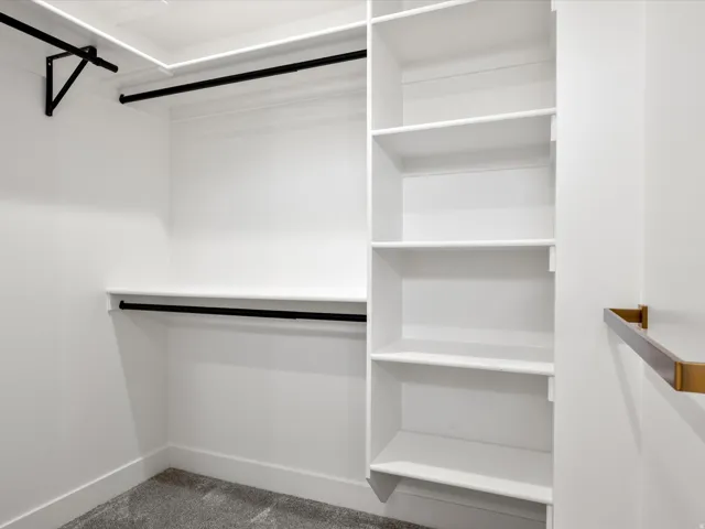 Custom closet organization system featuring white shelving, black hanging rods, and a built-in shelving unit