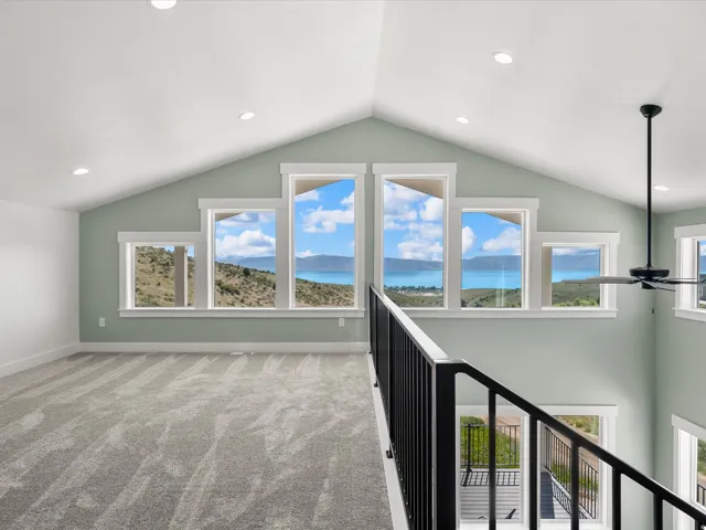 Open loft area featuring a vaulted ceiling with recessed lighting, light green wall paint, and gray carpeting