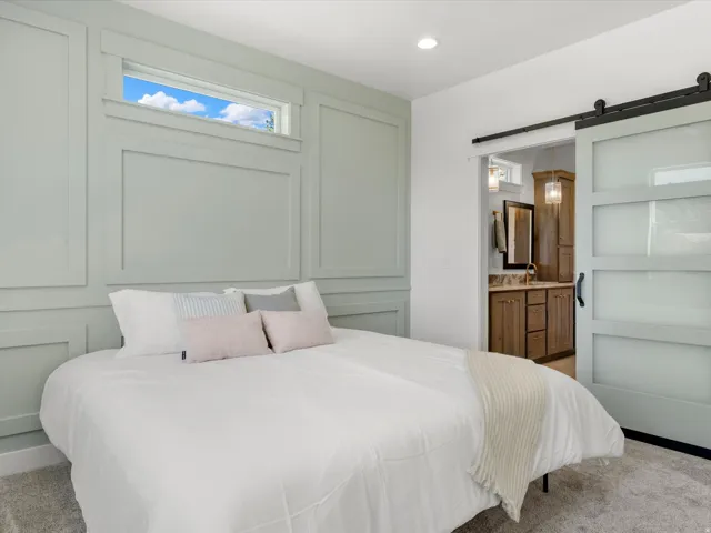 Bedroom featuring wainscoting and a transom window, with a barn door leading to a bathroom