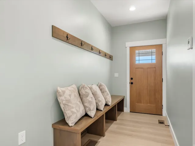 Entryway featuring a solid wood door with a clear glass insert, a built-in wood bench, and light wood-finish flooring