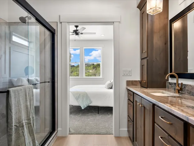 Bathroom featuring a glass-enclosed shower with dark trim, a wood vanity with a stone countertop and integrated sink, and an overhead light fixture