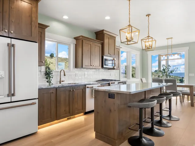 Gourmet kitchen featuring a large central island with seating, wood-finish cabinetry, light-toned wood-finish flooring, and a subway tile backsplash