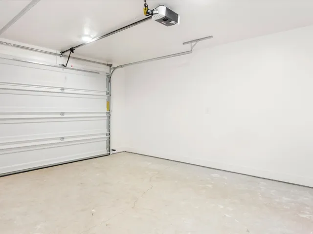 Attached garage featuring a white sectional door, painted interior walls, and a concrete floor
