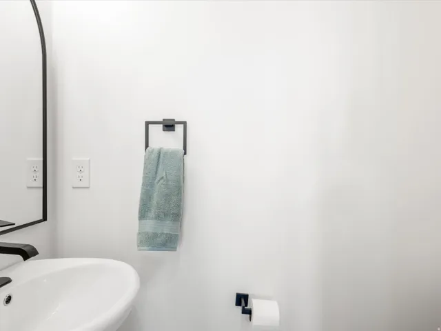 Pedestal sink with a matte black faucet, complemented by a contemporary wall-mounted mirror