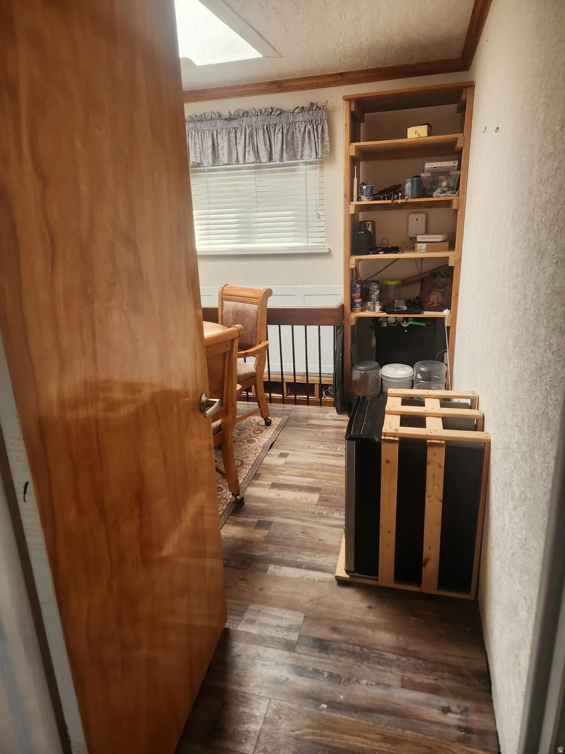 Bedroom with dark wood-type flooring, ornamental molding, a textured wall, and a textured ceiling
