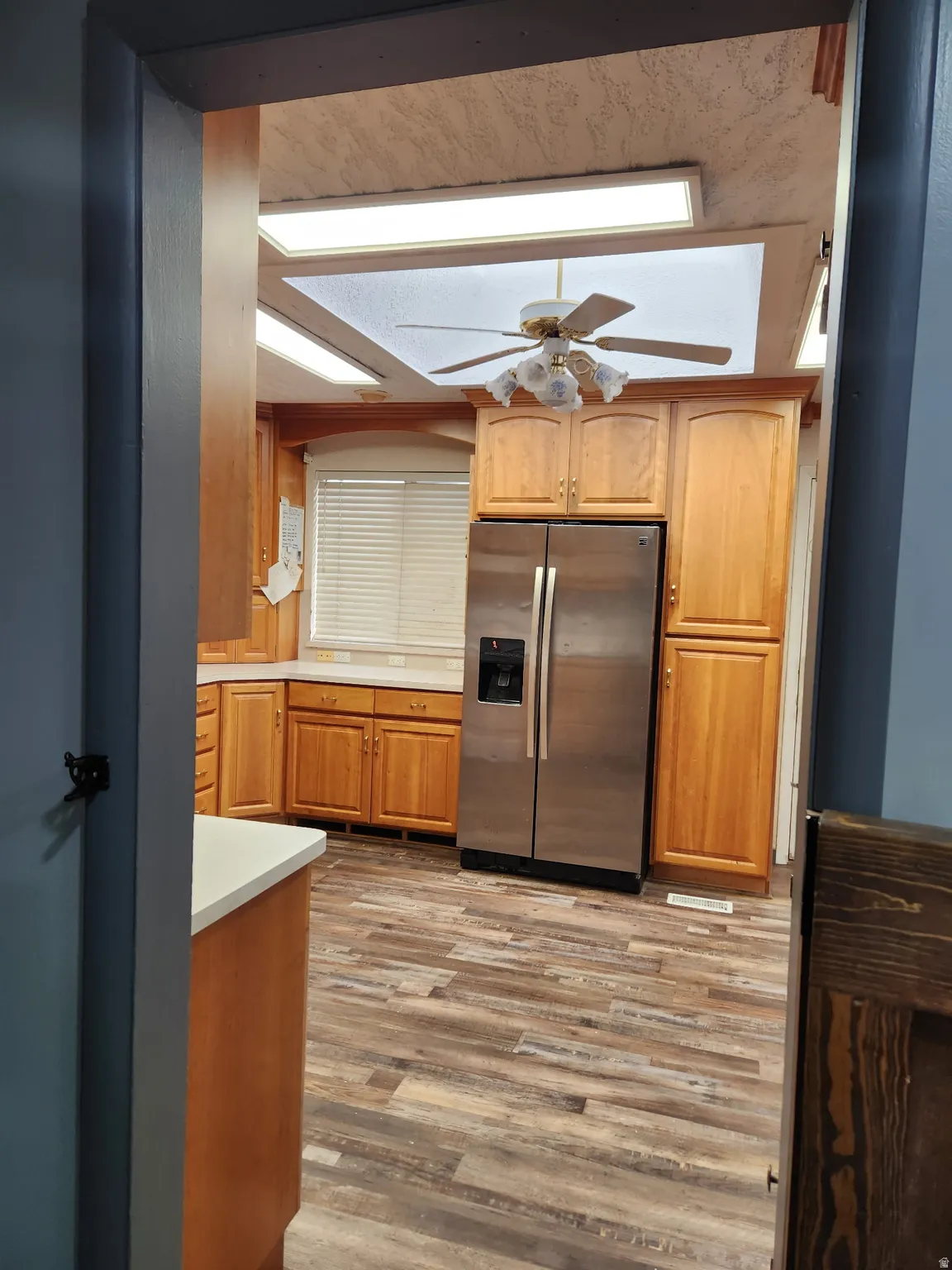 Kitchen with stainless steel fridge with ice dispenser, light countertops, light wood-style floors, and ceiling fan